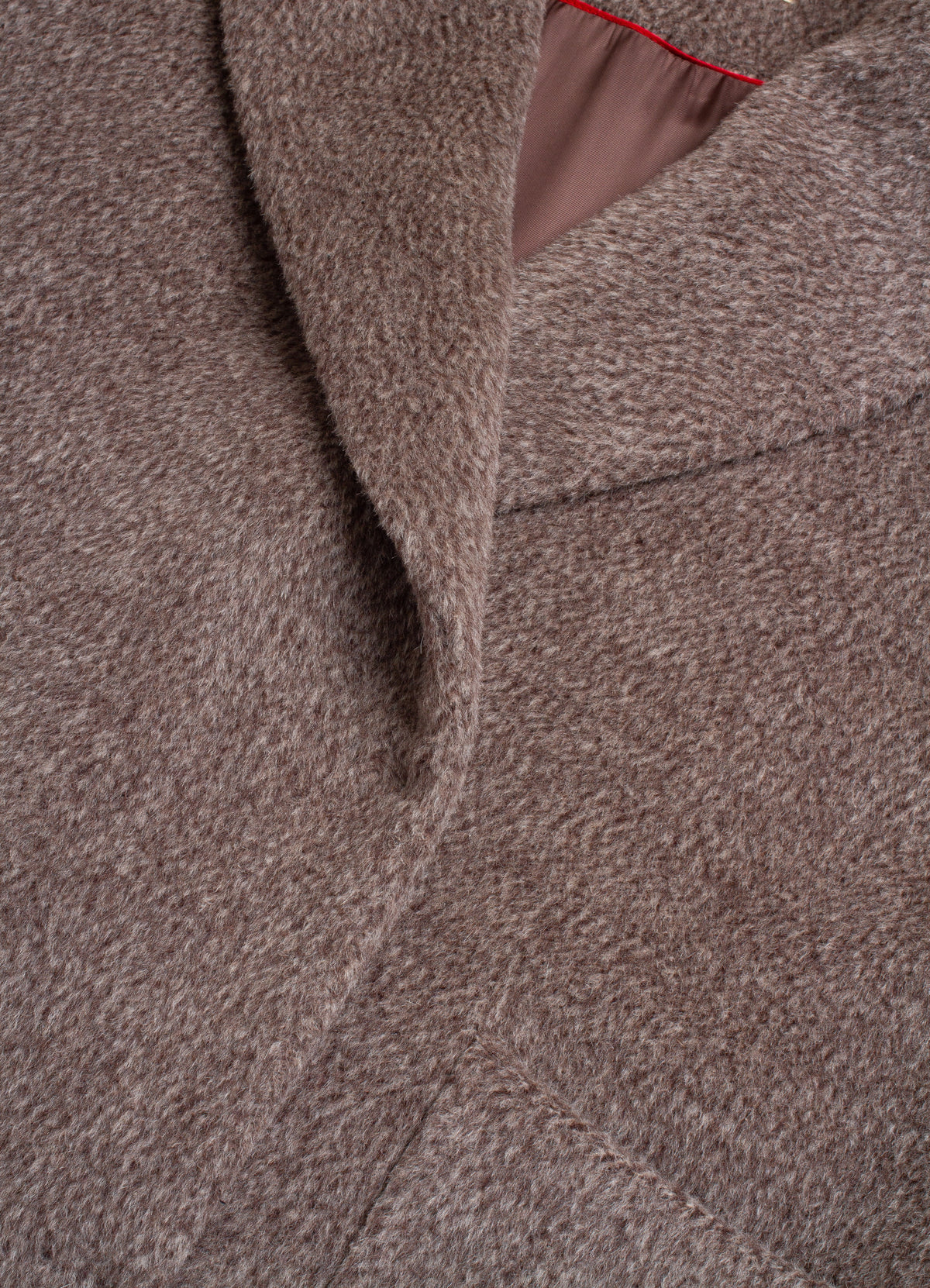 Close-up of a textured brown wool coat with a soft lapel and a glimpse of a pink lining.