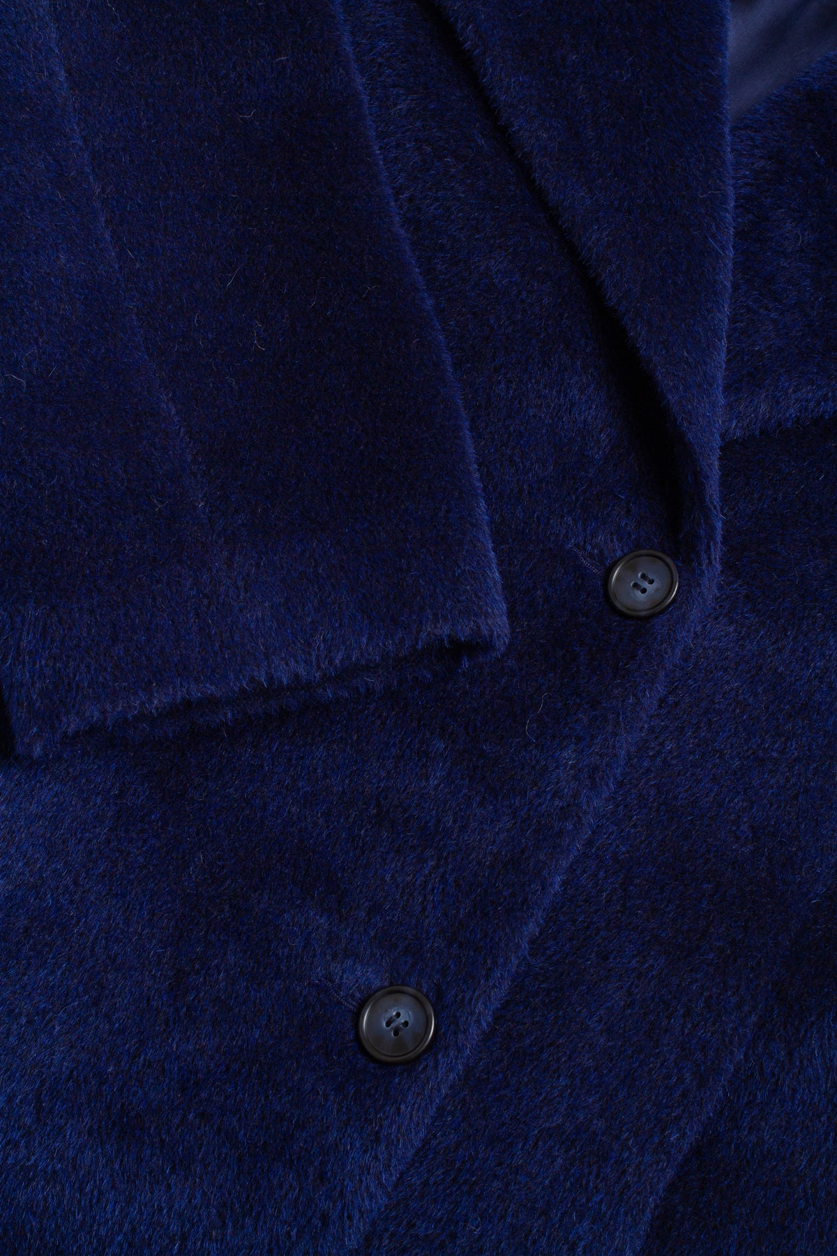 Close-up of a blue coat with buttons on a dark background