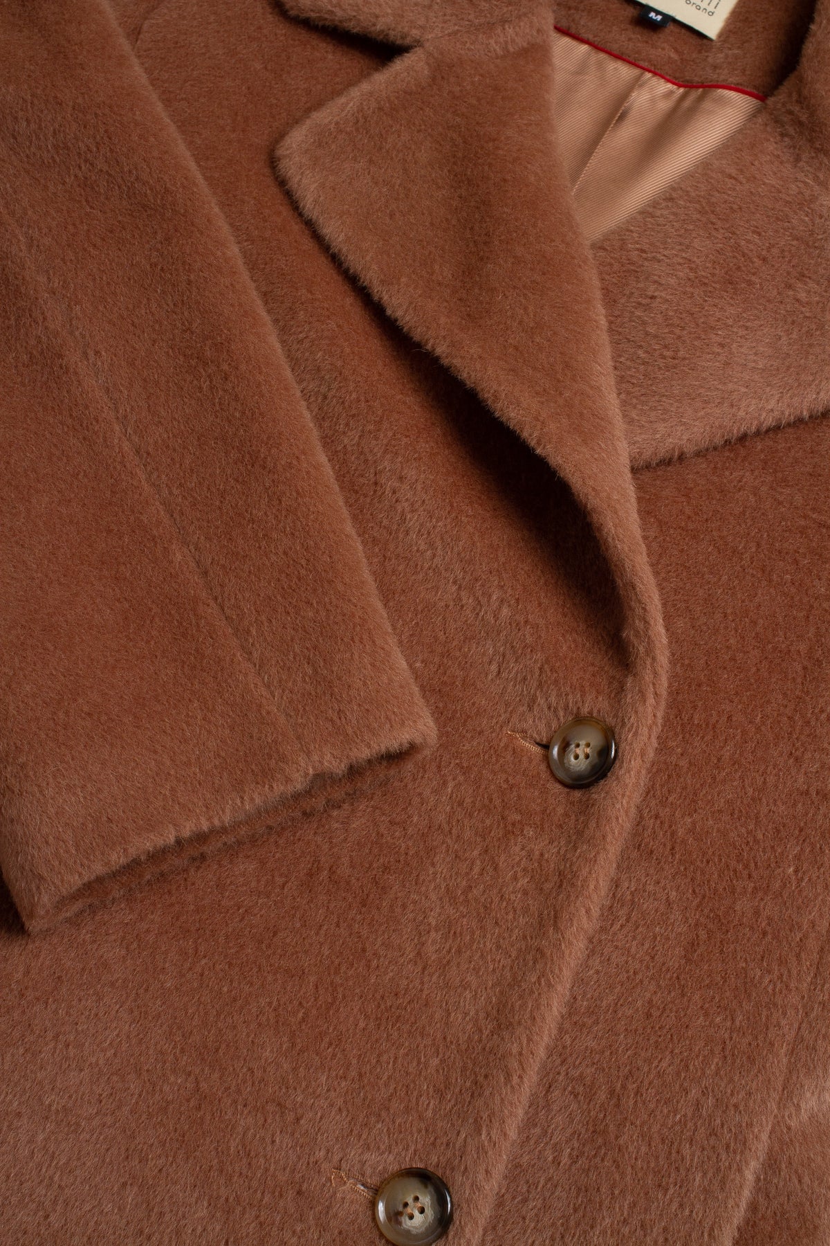 Close-up of a brown coat with buttons and collar details.