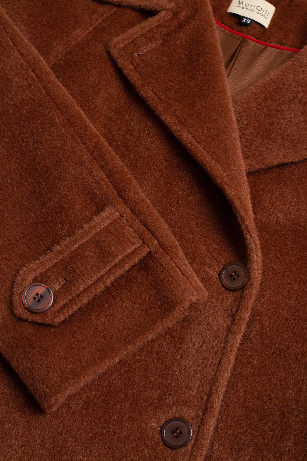 Close-up of a brown coat with buttons and a brand label.