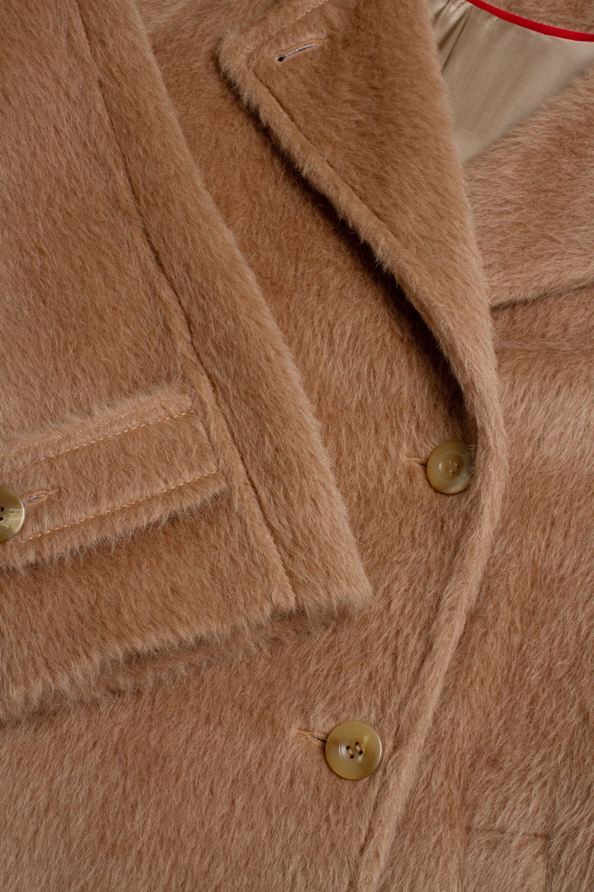 Close-up of a camel brown faux fur coat with gold buttons and a collar detail.