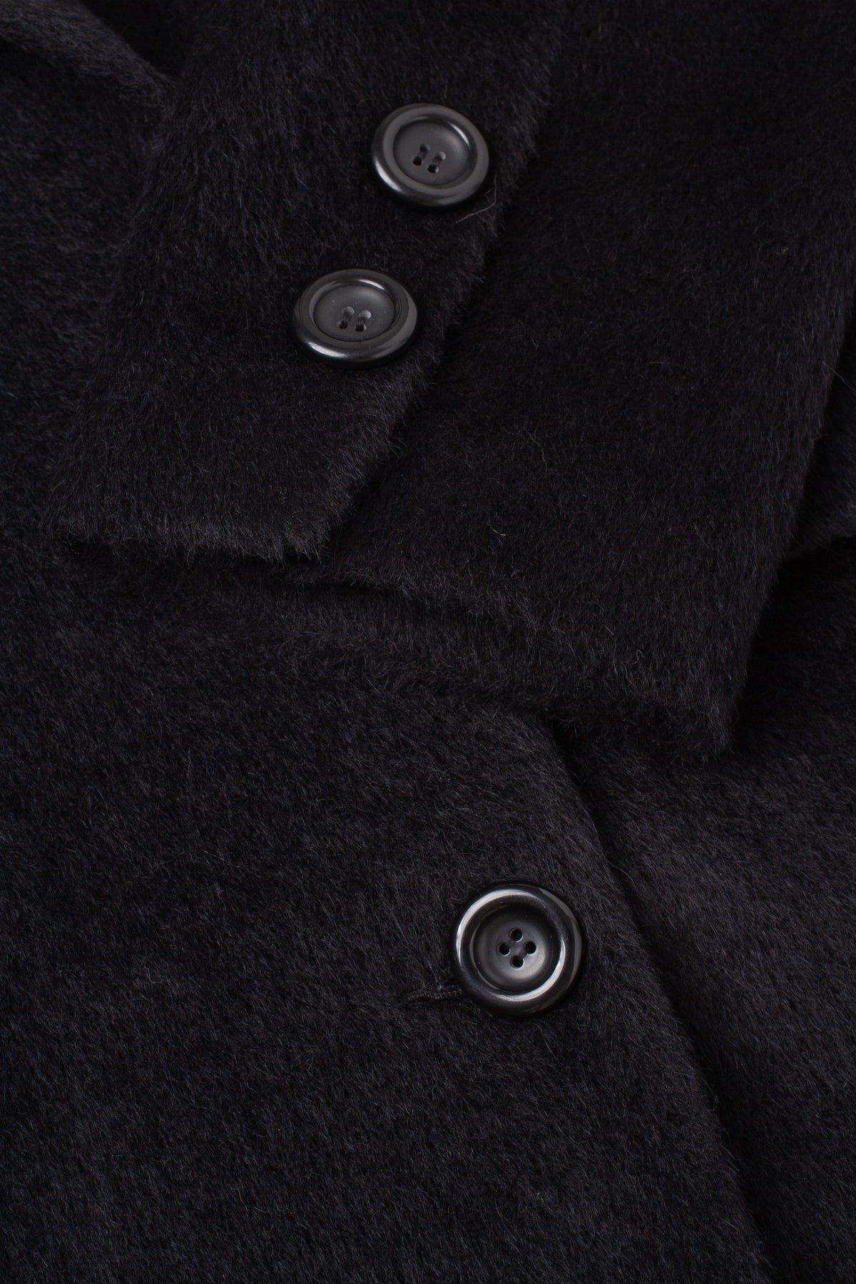 Close-up of a black textured wool or cashmere coat with dark buttons and a folded collar.